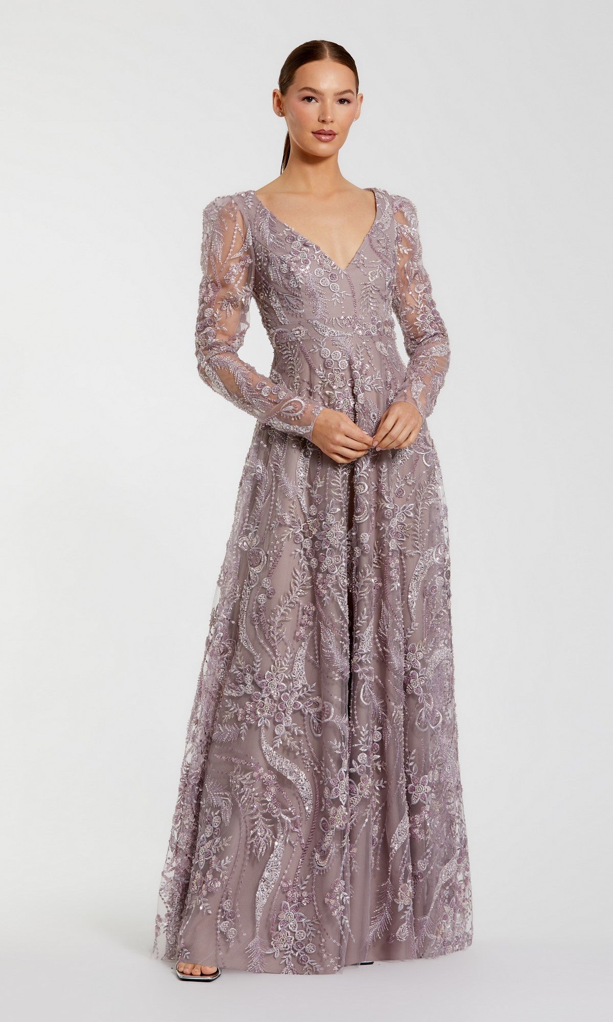 Dressed in the Mac Duggal 68908 long formal gown in vintage lilac, a woman poses elegantly against a plain white background. Featuring sheer sleeves and intricate embroidery, this exquisite dress is a stunning choice for a mother-of-the-bride.